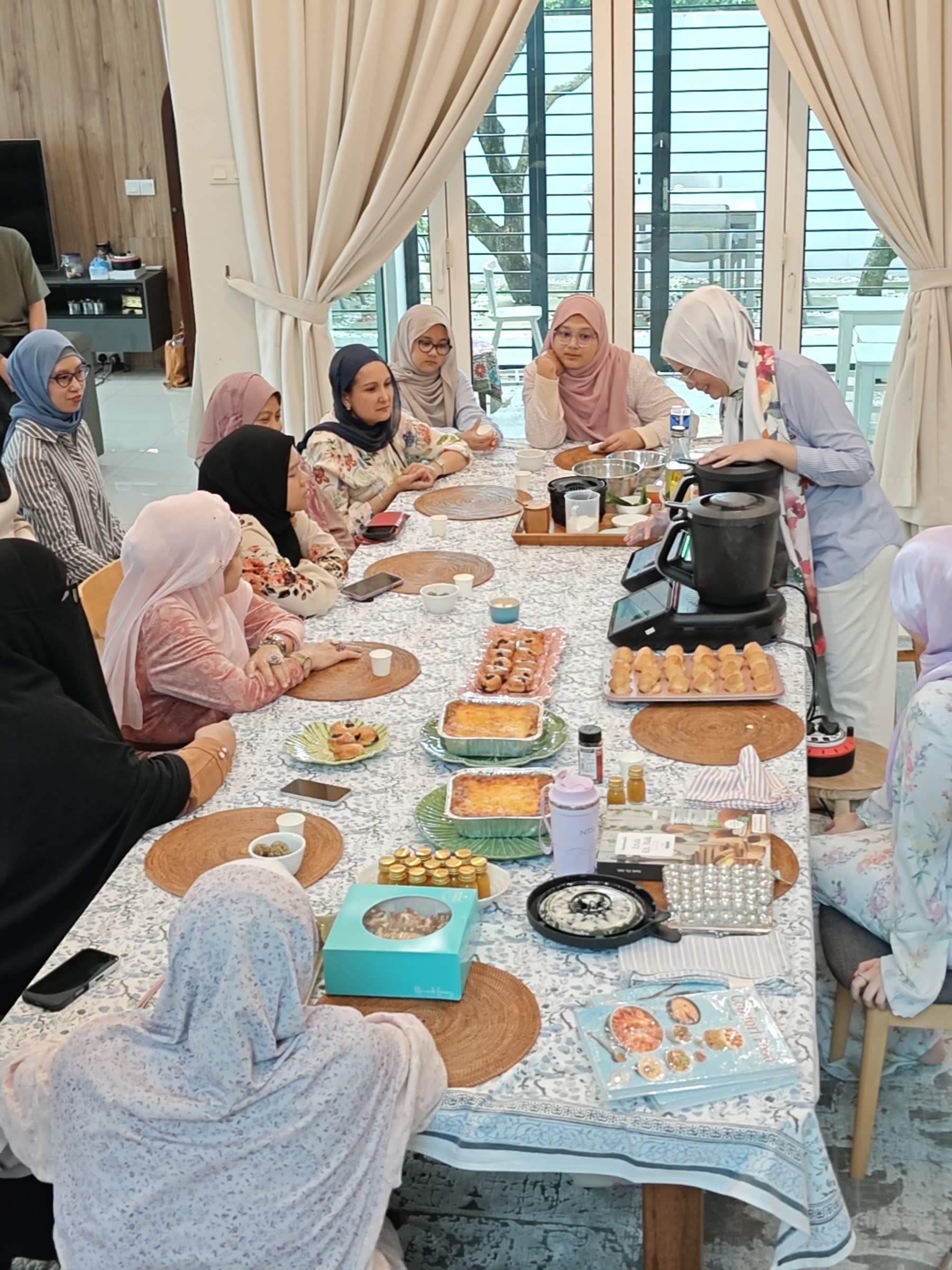 A CooknShare advisor demonstrating the Thermomix® at a long table of students during a home class